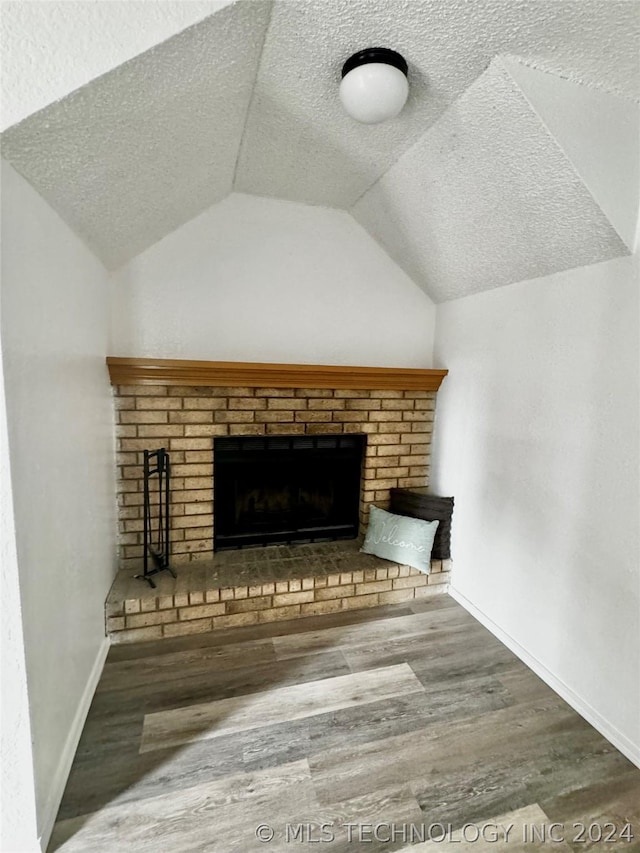 interior space with a brick fireplace and wood-type flooring