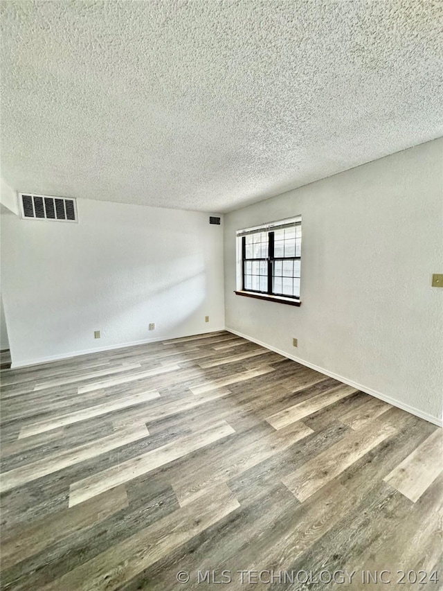 empty room featuring a textured ceiling and hardwood / wood-style flooring