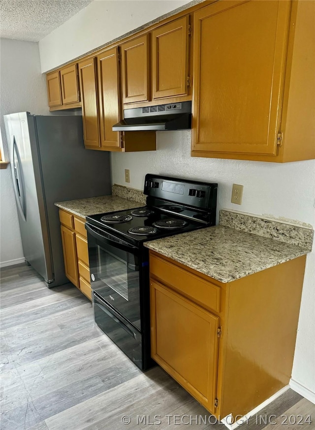 kitchen featuring black electric range, light wood-type flooring, light stone countertops, stainless steel fridge with ice dispenser, and a textured ceiling