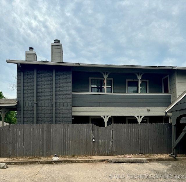 view of side of home featuring brick siding, a chimney, and fence