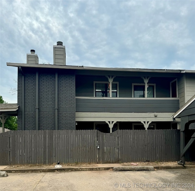 view of front of house featuring brick siding, a chimney, and a fenced front yard
