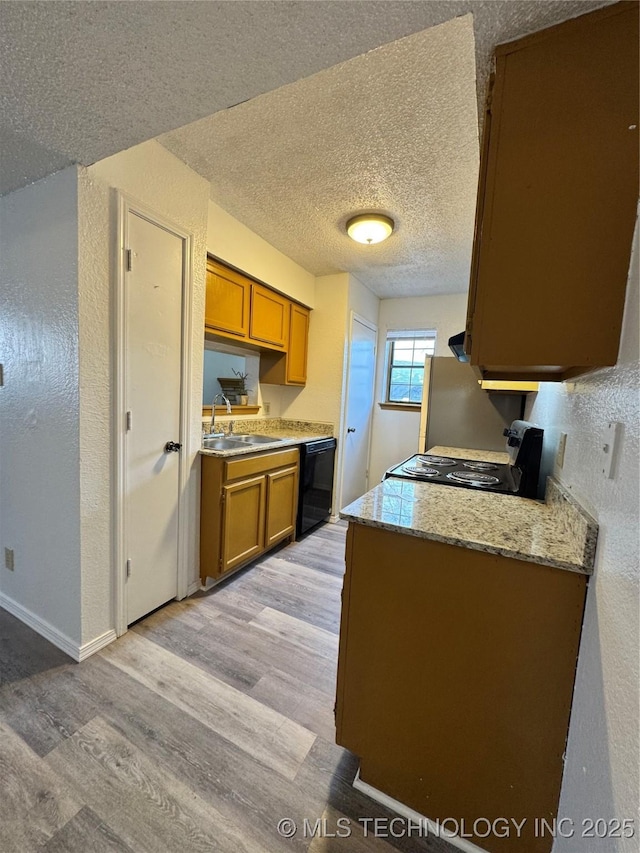 kitchen with black dishwasher, range with electric cooktop, brown cabinetry, and a sink