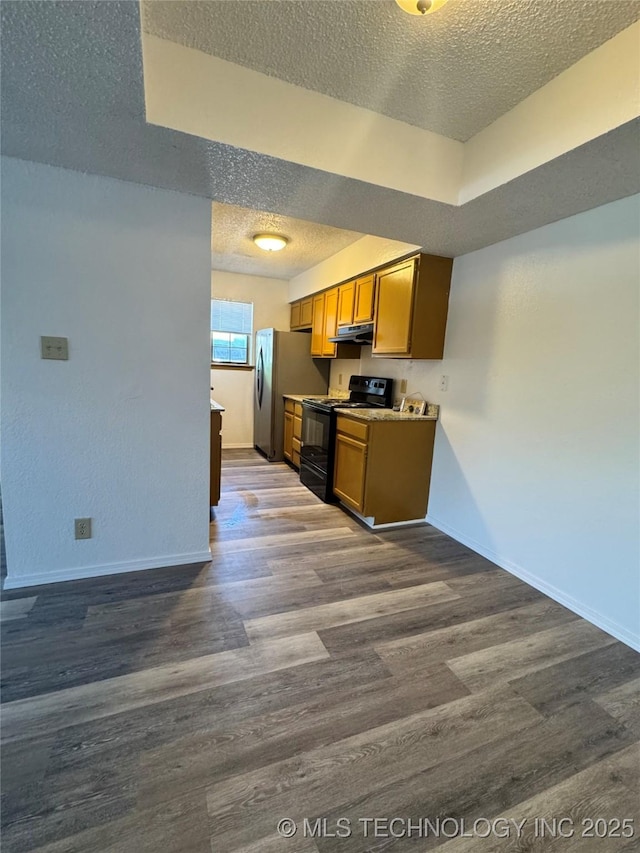 kitchen with under cabinet range hood, electric range, freestanding refrigerator, a textured ceiling, and dark wood-style flooring