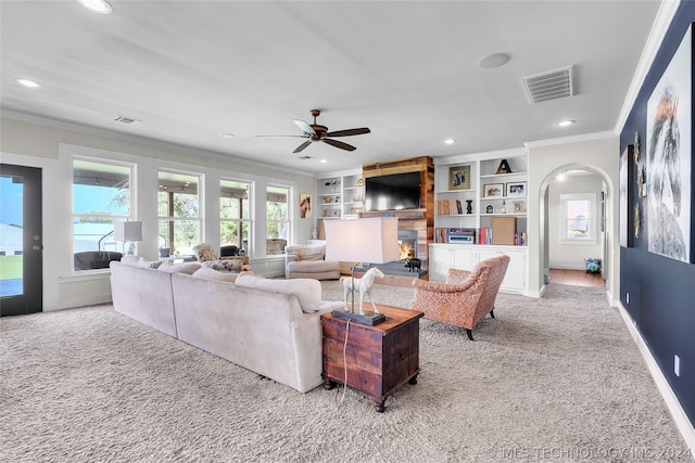 living room featuring light carpet, built in shelves, crown molding, and ceiling fan