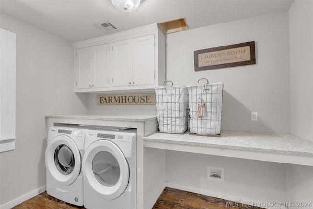 laundry room featuring washing machine and clothes dryer, cabinets, and dark wood-type flooring