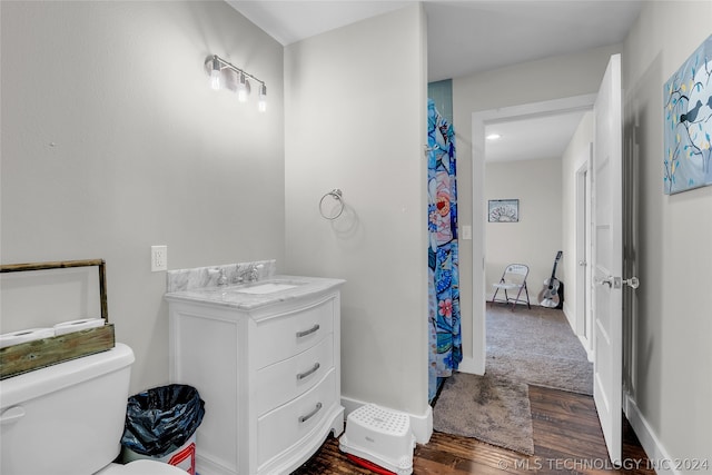 bathroom with hardwood / wood-style flooring, toilet, and vanity