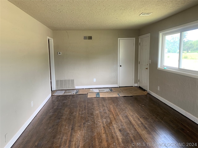 unfurnished room with a textured ceiling and wood-type flooring