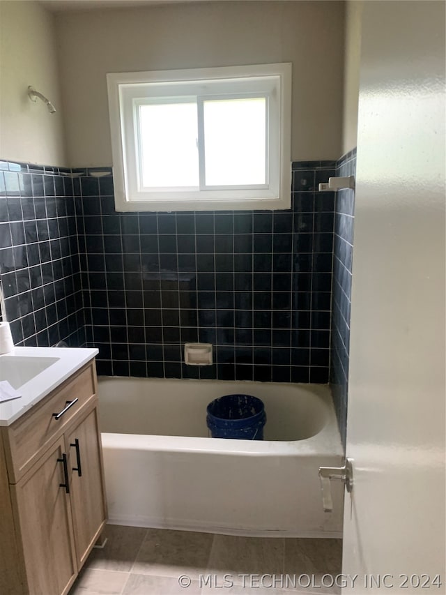 bathroom with tile patterned flooring, tile walls,  shower combination, and vanity