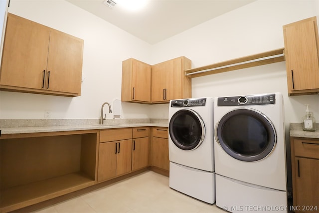 clothes washing area with light tile patterned flooring, cabinets, washer and clothes dryer, and sink