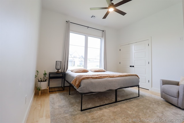 bedroom featuring light wood-type flooring, ceiling fan, and a closet