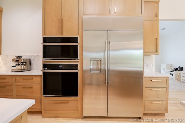 kitchen with light hardwood / wood-style flooring, built in fridge, light brown cabinetry, and double oven