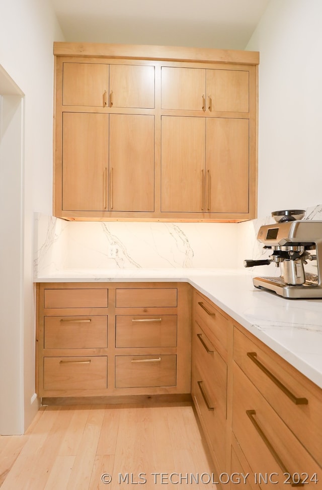 kitchen with light brown cabinetry, light stone counters, and light hardwood / wood-style floors