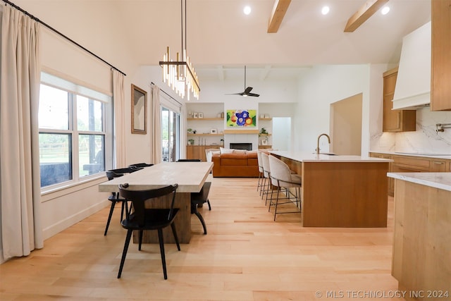 dining room featuring light hardwood / wood-style floors, sink, beam ceiling, and ceiling fan