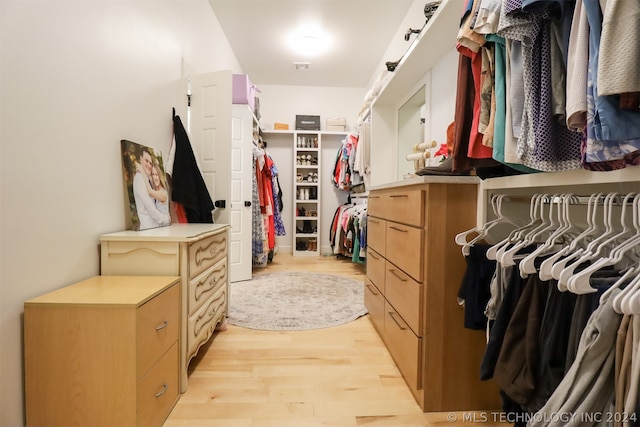 walk in closet with light hardwood / wood-style floors