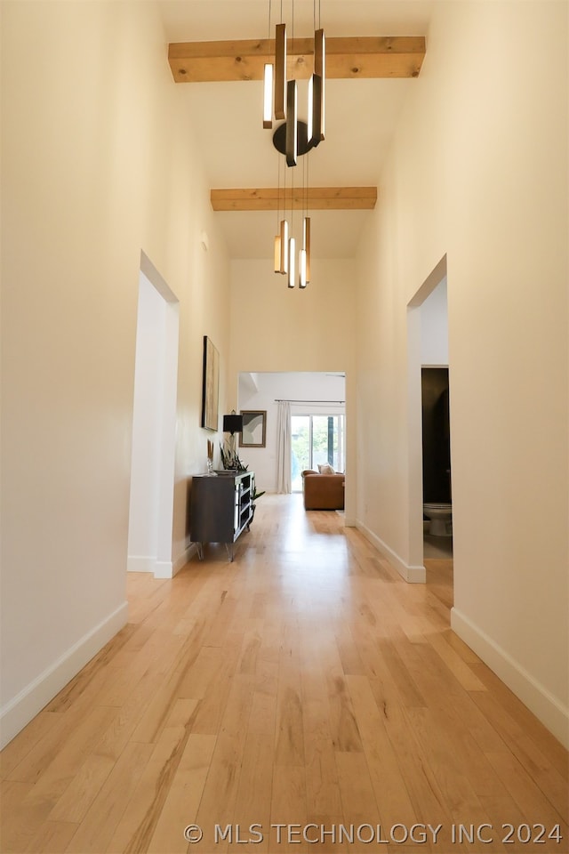 interior space featuring a chandelier, beamed ceiling, light wood-type flooring, and high vaulted ceiling