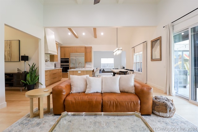 living room with beamed ceiling, a notable chandelier, light hardwood / wood-style flooring, and high vaulted ceiling