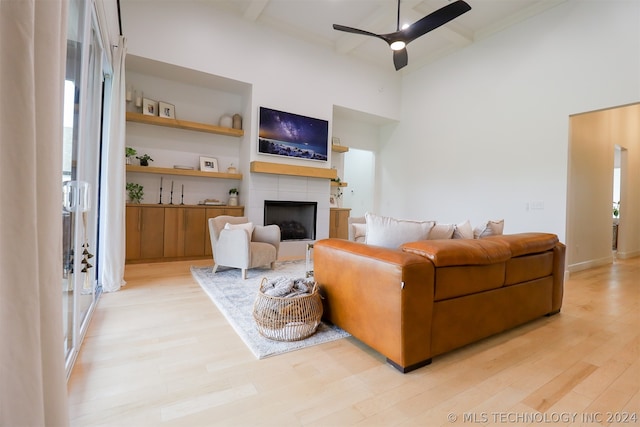 living room featuring a tile fireplace, ceiling fan, and light hardwood / wood-style floors