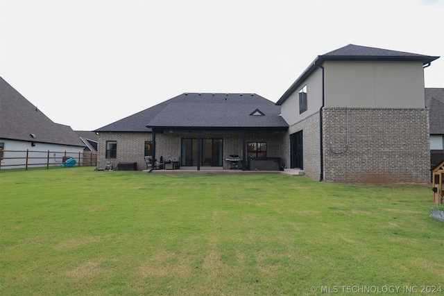 back of property with a patio area and a lawn