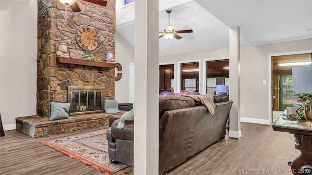 living room featuring ceiling fan, hardwood / wood-style floors, vaulted ceiling, and a fireplace