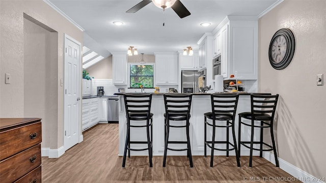 kitchen featuring tasteful backsplash, white cabinets, a breakfast bar, stainless steel appliances, and lofted ceiling