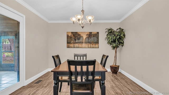 dining area featuring wood-type flooring, crown molding, and a notable chandelier