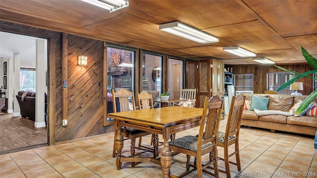 dining space featuring wood walls, wood ceiling, and light tile patterned flooring