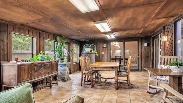 dining area featuring light tile patterned floors, wood ceiling, and wooden walls