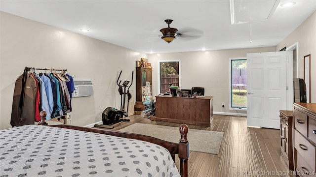 bedroom with ceiling fan, hardwood / wood-style floors, and a wall unit AC