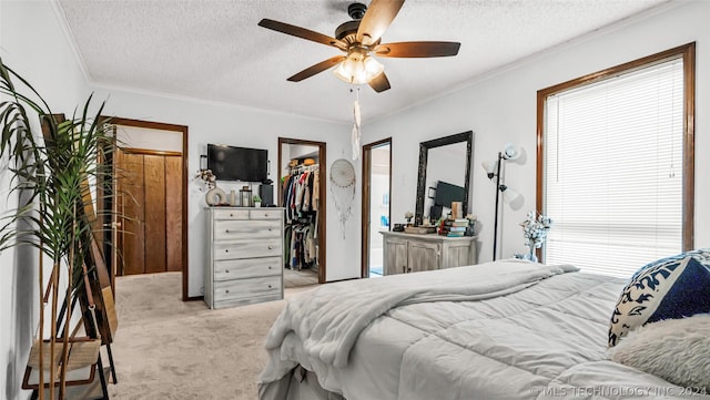 bedroom featuring a textured ceiling, a walk in closet, light carpet, ceiling fan, and multiple windows