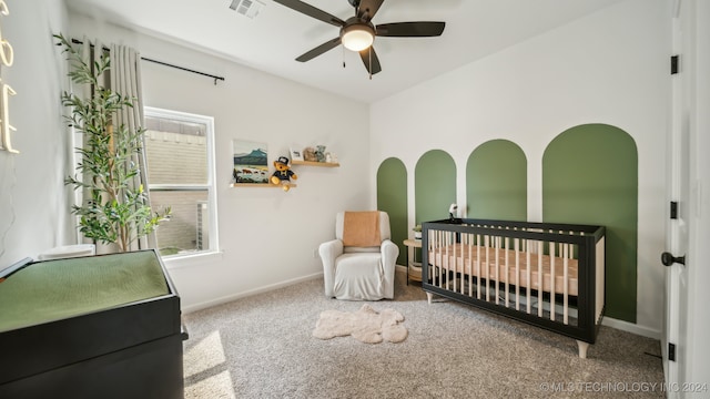 bedroom with carpet floors, a crib, and ceiling fan