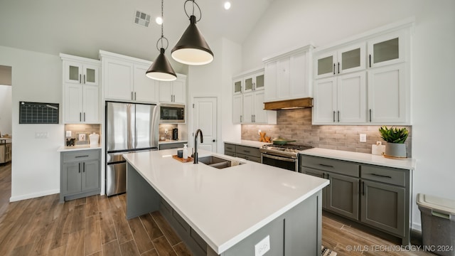 kitchen featuring pendant lighting, a kitchen island with sink, stainless steel appliances, and white cabinets