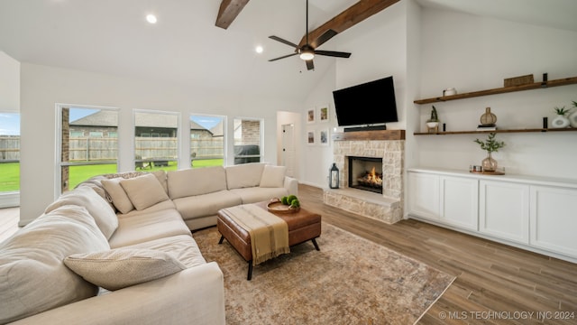 living room with beam ceiling, ceiling fan, high vaulted ceiling, a fireplace, and light hardwood / wood-style floors