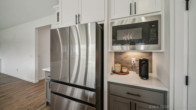 kitchen with white cabinets, dark hardwood / wood-style flooring, gray cabinets, appliances with stainless steel finishes, and tasteful backsplash