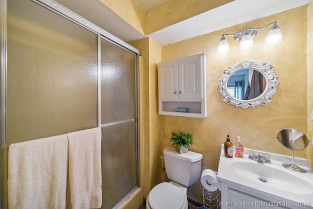 bathroom featuring a shower with door, vanity, and toilet