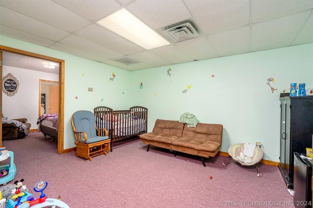 bedroom featuring a crib, a drop ceiling, and carpet