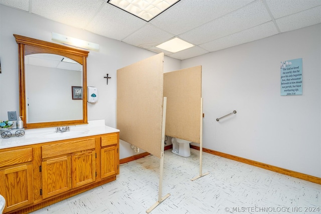 bathroom with a drop ceiling, toilet, and vanity