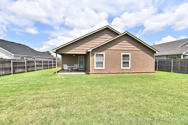 rear view of property featuring a yard and a patio area