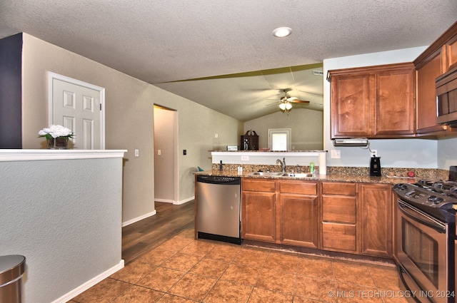 kitchen with lofted ceiling, ceiling fan, dark stone counters, sink, and stainless steel appliances