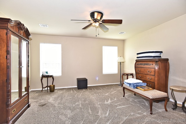 living area featuring ceiling fan and dark colored carpet