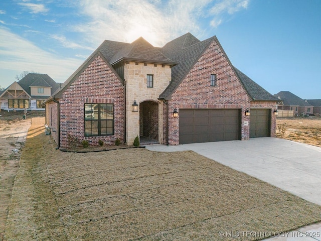 view of front of home with driveway, brick siding, stone siding, roof with shingles, and a front yard