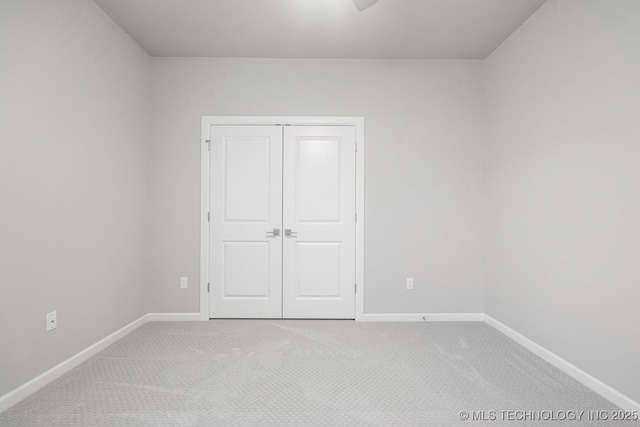 unfurnished bedroom with baseboards, a closet, and light colored carpet