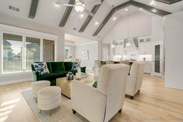 living room with visible vents, baseboards, light wood-style flooring, beamed ceiling, and high vaulted ceiling