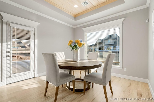 dining area featuring light wood-style flooring, a tray ceiling, and ornamental molding