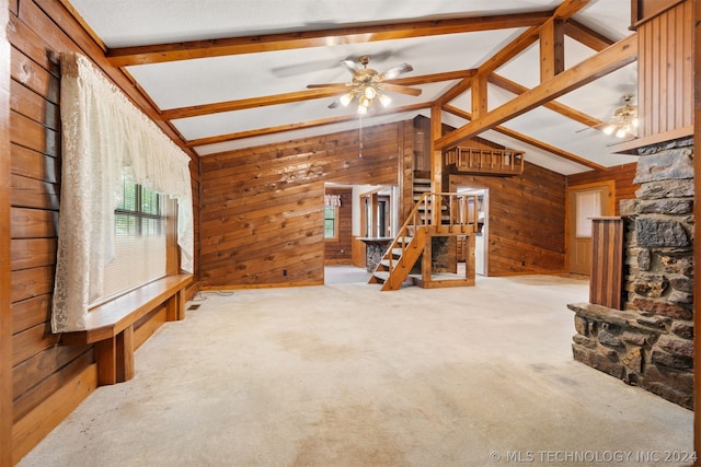 unfurnished living room featuring vaulted ceiling with beams, carpet flooring, ceiling fan, and wooden walls