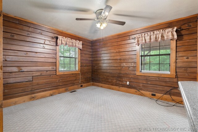 carpeted spare room featuring ceiling fan and wooden walls