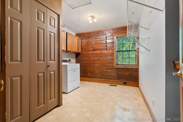 laundry room featuring washer / clothes dryer, light tile patterned floors, wood walls, and cabinets