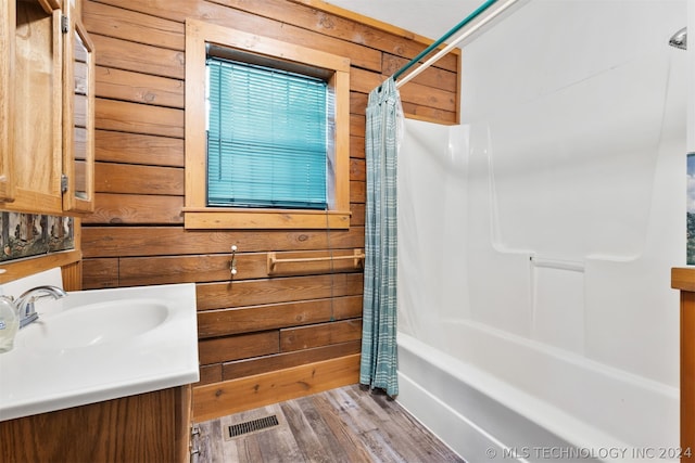 bathroom with vanity, wood walls, hardwood / wood-style flooring, and shower / bath combo