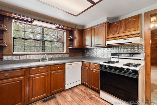 kitchen with sink, tasteful backsplash, white appliances, and light hardwood / wood-style floors