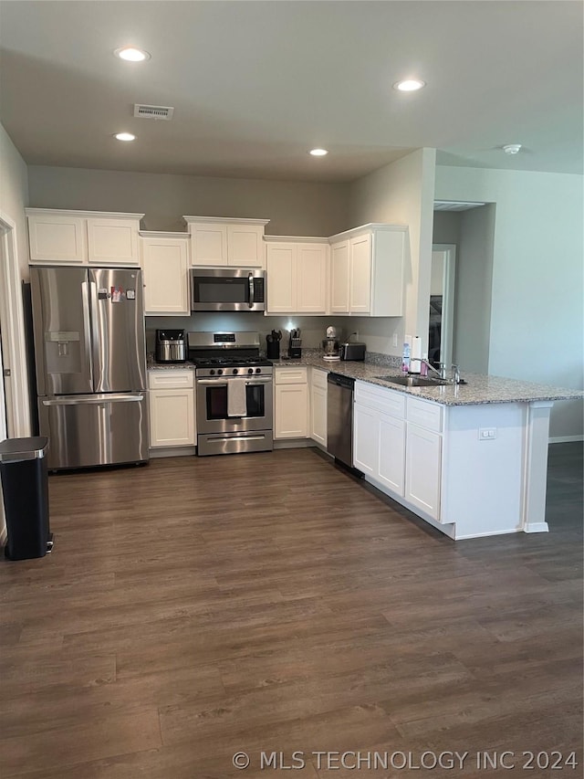 kitchen featuring light stone counters, appliances with stainless steel finishes, kitchen peninsula, and white cabinets