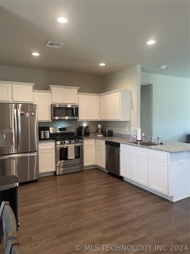 kitchen with sink, light stone counters, appliances with stainless steel finishes, dark hardwood / wood-style flooring, and white cabinets